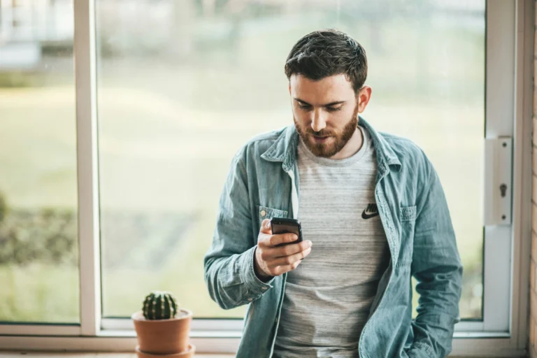 Man leaning on a side looking at phone. Our featured image for our article on 'gambling self-exclusion'