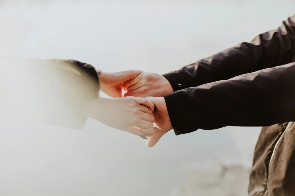 People holding hands showing support to each other. Our featured image for our article on 'how to help someone with a gambling problem'